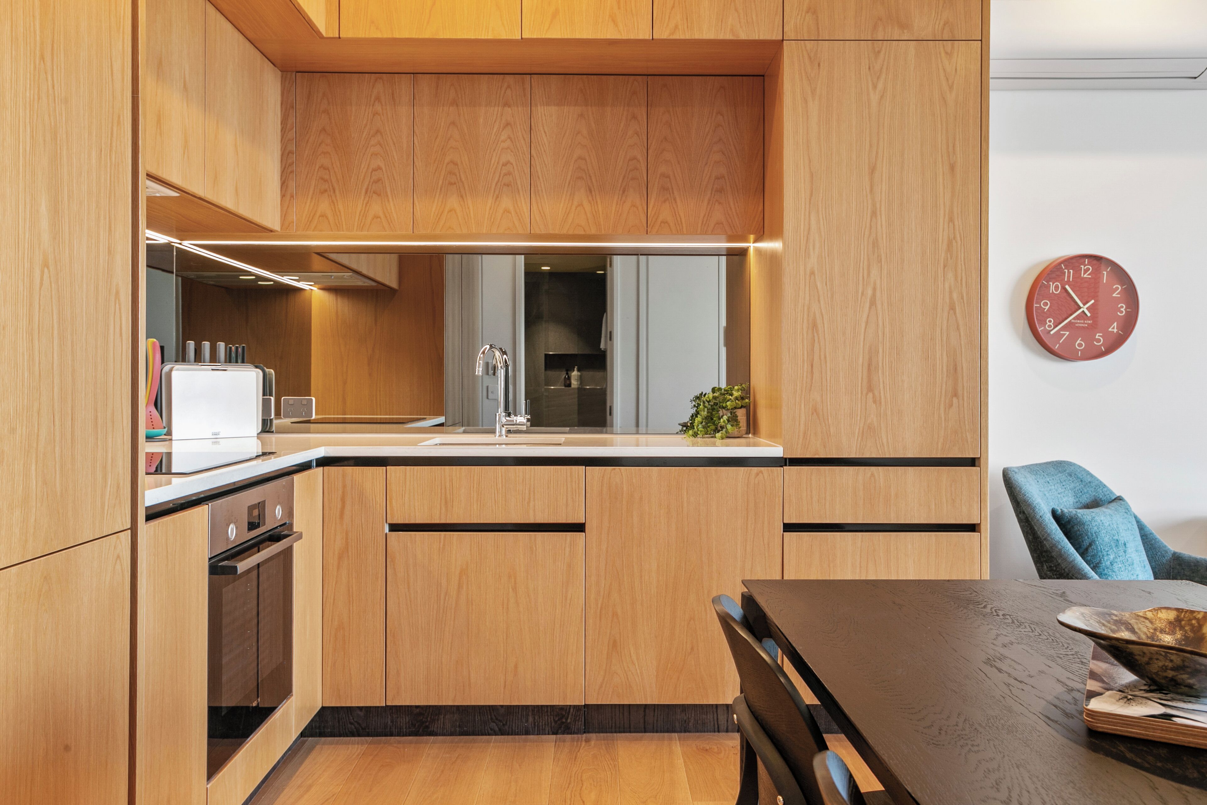 A modern kitchen with wooden cabinets, a built-in oven, and a sink.