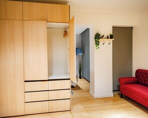 A modern living room with a red sofa, wooden wardrobe, and a hallway leading to another room. - Lastarria Suites (Santiago)