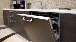 A modern kitchen with a dishwasher integrated into a cabinet, a coffee maker, and a sink.