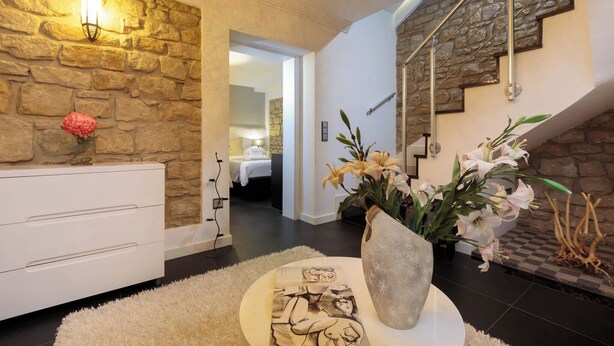 A modern interior with a stone wall, a staircase, and a white console table with a vase of flowers.