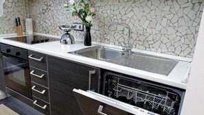 Una cocina moderna con lavavajillas integrado, un lavamanos de acero inoxidable y un salpicadero de mosaicos.