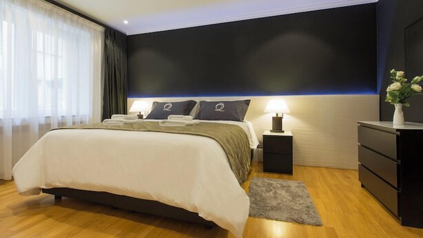 Un dormitorio moderno con una cama grande, dos mesitas de noche, un aparador y una cómoda.