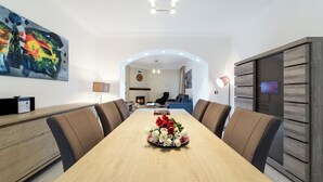 Ein moderner Essbereich mit einem langen Tisch, bequemen Stühlen und einem Blumenarrangement in der Mitte.