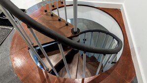 A spiral staircase with a wooden finish and metal handrails.