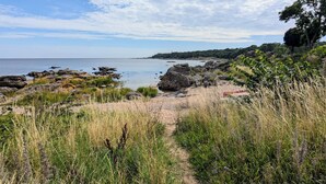 Ett kustlandskap med en stenig strand, gräsbevuxna områden och fri utsikt över havet.