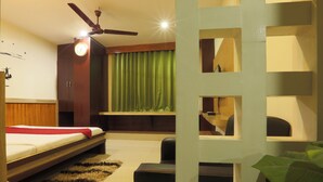 A modern bedroom with a bed, a ceiling fan, a green curtain, and built-in shelves.