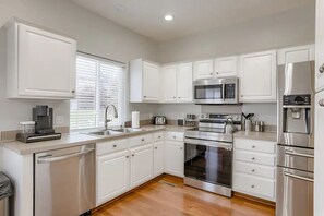 Una cocina moderna con armarios blancos, electrodomésticos de acero inoxidable y lavavajillas.