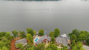 Vista aérea de uma área residencial com um grande lago, casas com piscina e um píer.