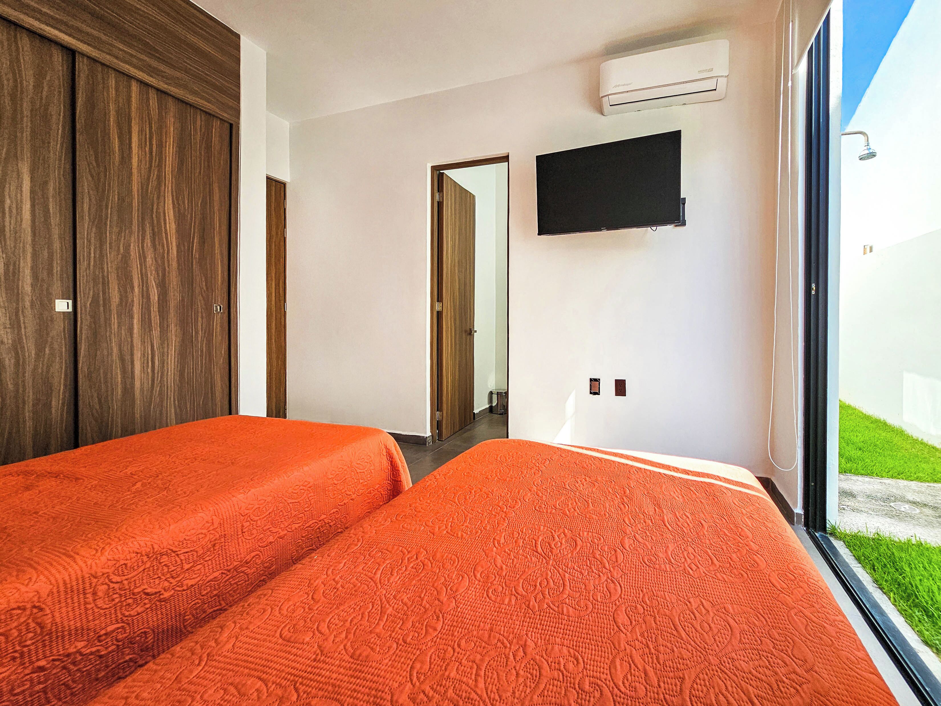 A hotel room with two beds, a TV, and a large window.
