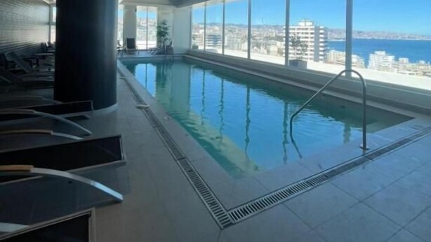 Una piscina interior con vistas a la ciudad y al mar.