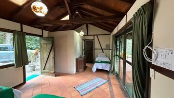 A room with a bed, a small table, a window, and a ceiling fan.