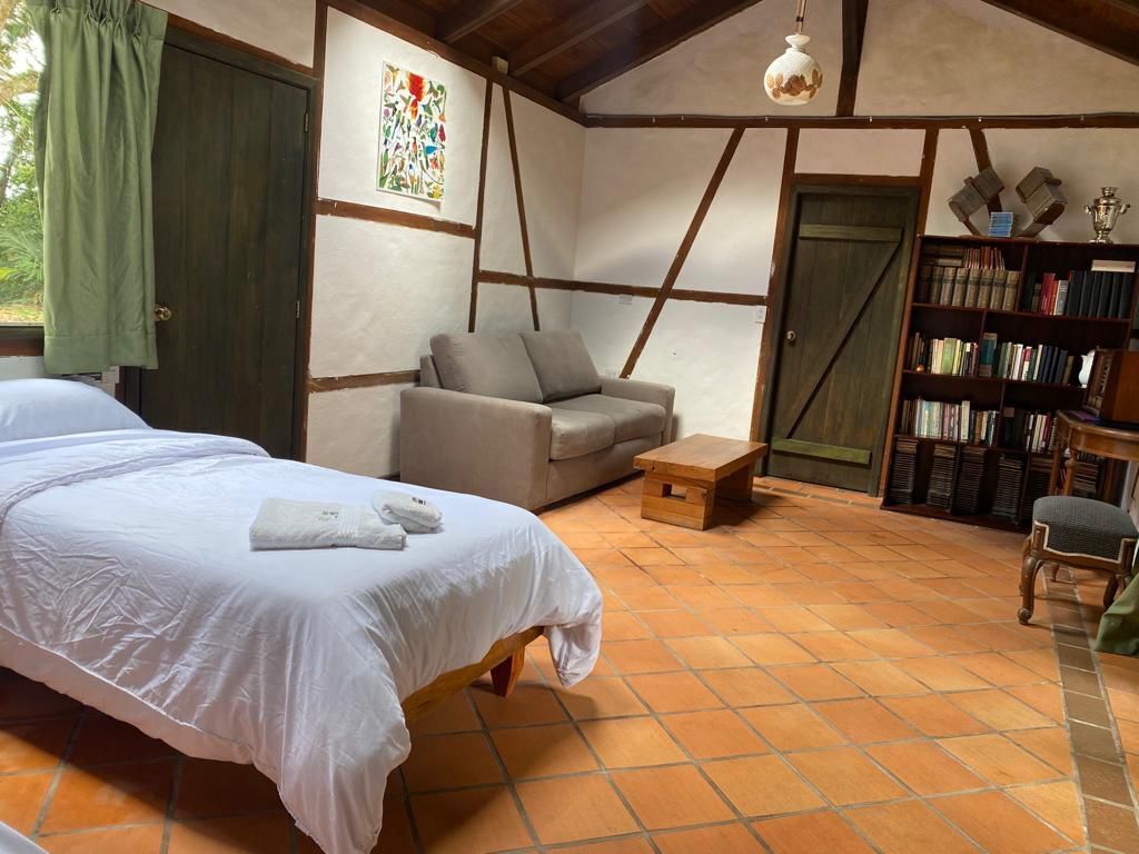 Een slaapkamer met een bed, een bank, een tafeltje, een boekenkast en een deur.