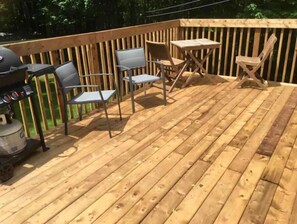 A wooden deck with a grill, two metal chairs, and a small table. - Beautiful split entry home in a wooded paradise!
 (Kensington)