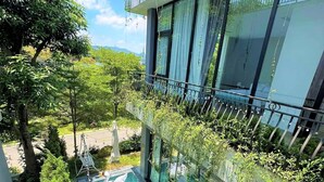 A modern building with a glass facade, a rooftop garden, and a swimming pool with a hot tub.