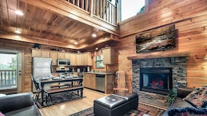A cabin interior with a wooden interior, a stone fireplace, a dining area, and a kitchen with modern appliances. - Free Dollywood Tix/Pool/15Min2Dollywood/Pool table (PIgeon Forge)