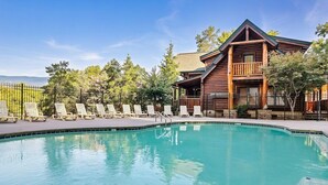 A pool area with lounge chairs and a wooden lodge building. - Free Dollywood Tix/Pool/15Min2Dollywood/Pool table (PIgeon Forge)