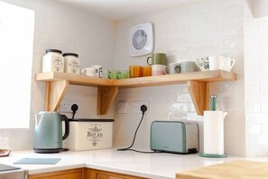 Kitchen features a clean layout with a shelf for kitchenware, a bread box, toaster, and kettle.