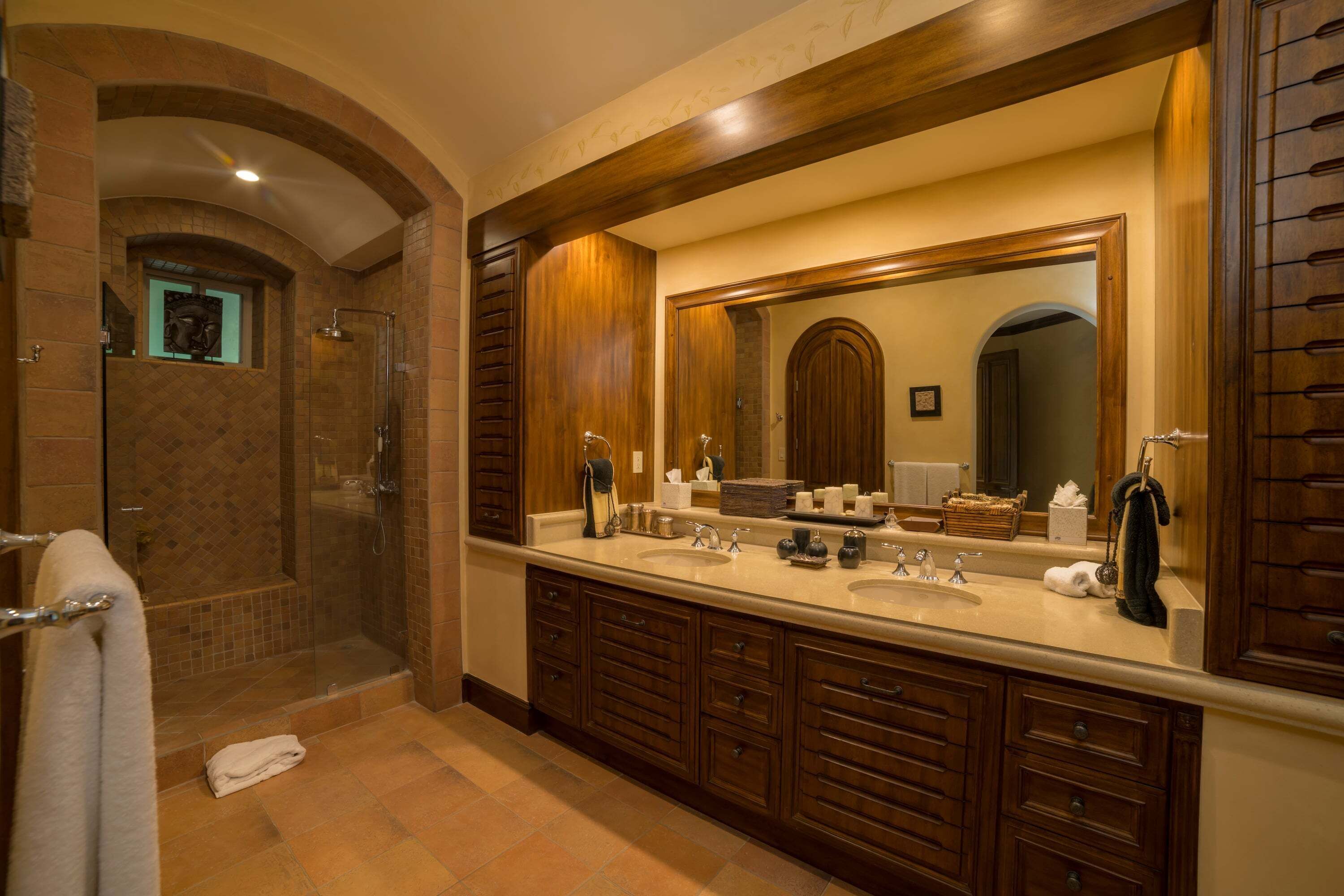 Une salle de bain dotée d’un grand miroir, de deux lavabos, d’une douche et de meubles en bois.