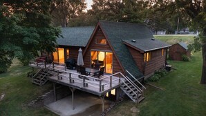 A cabin with a deck, a covered outdoor seating area, and a staircase leading to the entrance.