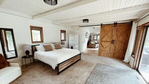 A spacious bedroom with a large bed, a wooden wardrobe, a washing machine, and a view of the outdoors.