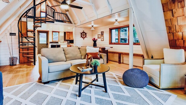 A spacious loft with a curved staircase, a cozy living area with a sofa and coffee table, and a view of the outside.