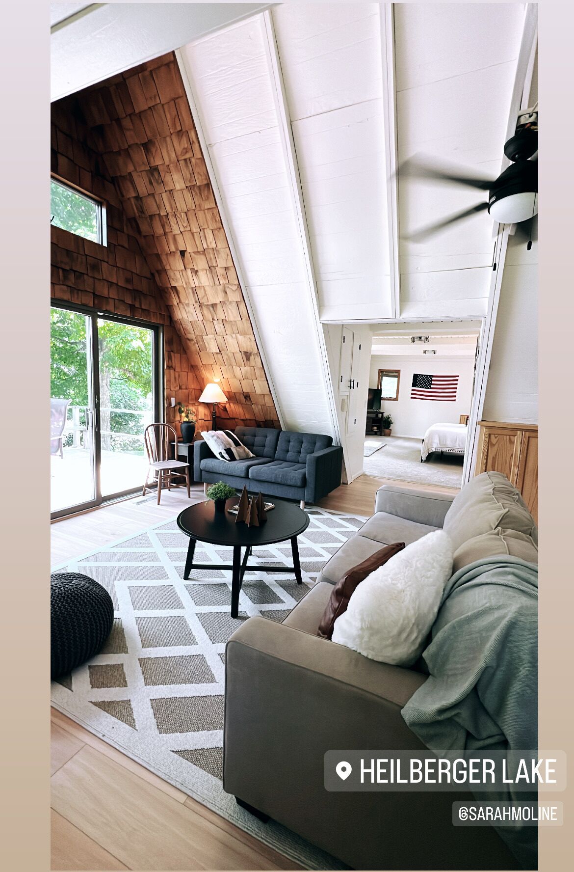 A modern living room with a sloped ceiling, a sofa, a coffee table, and a view of the outdoors.