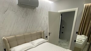 Een moderne hotelkamer met een groot bed, een klein rond tafeltje en een spiegel in de badkamer.