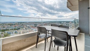 A balcony with a table and chairs, offering a city view.