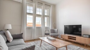 A modern living room with a sofa, a coffee table, a TV, and a speaker. - Trendy Wieden 2BR w/ Balcony & Elevator, nr Shopping, by Blueground (Vienna)