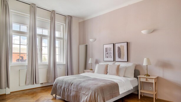 A bedroom with a large bed, two bedside tables, a mirror, and artwork on the wall. - Trendy Wieden 2BR w/ Balcony & Elevator, nr Shopping, by Blueground (Vienna)