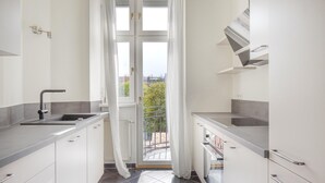 A modern kitchen with white cabinets, a stainless steel sink, and a view of the city through a large window. - Trendy Wieden 2BR w/ Balcony & Elevator, nr Shopping, by Blueground (Vienna)