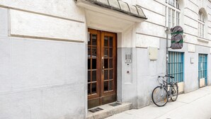 A building with a wooden door, a bicycle parked outside, and a blue door in the background. - Trendy Wieden 2BR w/ Balcony & Elevator, nr Shopping, by Blueground (Vienna)