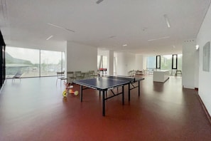 A spacious room with a ping pong table, chairs, and a view of the city through large windows. - Lovely Landstraße 1BR w/ Gym & Balcony, nr Shops & Dining, by Blueground (Vienna)