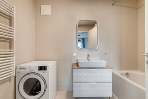 Ein modernes Badezimmer mit Waschmaschine, Waschbecken und Badewanne.