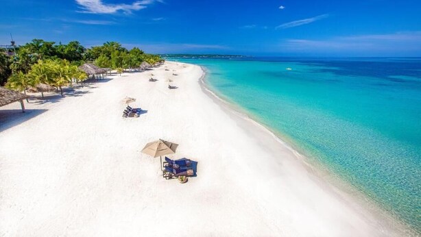 A beach with white sand, clear turquoise water, and a few umbrellas and lounge chairs. - THE AQUEDUCTS OF NEGRIL
"Seaview Paradise" (Negril)