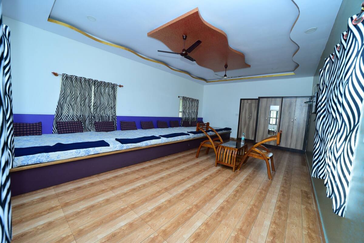 A room with a long wooden bench, a ceiling fan, and a zebra-patterned curtain.