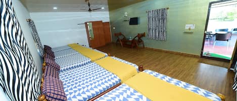 Hotellihuone, jossa on suuri sänky, kattotuuletin, televisio ja näkymä ulos.