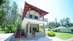 A two-story building with a red roof, a balcony, and a staircase leading to the entrance.