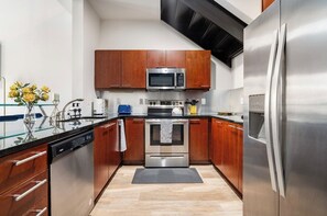 Kitchen features stainless steel appliances, a wood cabinetry, and a glass countertop.