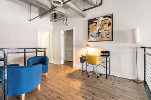 Relax in a stylish space with a comfortable seating area, workspace, and artistic touches.