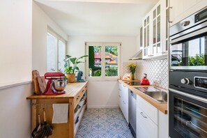 Une cuisine compacte avec une fenêtre, un batteur rouge, un évier et un four moderne.
