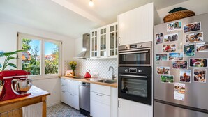 Una cocina moderna con armarios blancos, electrodomésticos de acero inoxidable y una ventana con vistas a casas.