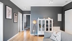 A modern living room with a grey sofa, a white cabinet, and framed artwork on the wall. - Holiday Apartment "B5" with Mountain View, Balcony & Wi-Fi (Bad Bellingen)
