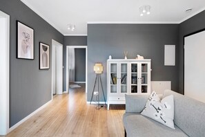 A modern living room with a grey sofa, a white cabinet, and framed artwork on the wall. - Holiday Apartment "B5" with Mountain View, Balcony & Wi-Fi (Bad Bellingen)