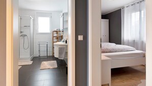 A modern bedroom with a bed, a bedside table, and a window with curtains. - Holiday Apartment "B5" with Mountain View, Balcony & Wi-Fi (Bad Bellingen)