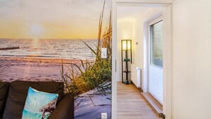 A beach-themed wall mural, a modern interior with a floor lamp, and a view through a window.