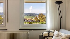 Una habitación con vistas a un paisaje rural, un radiador, una ventana con persianas y una lámpara de pie.