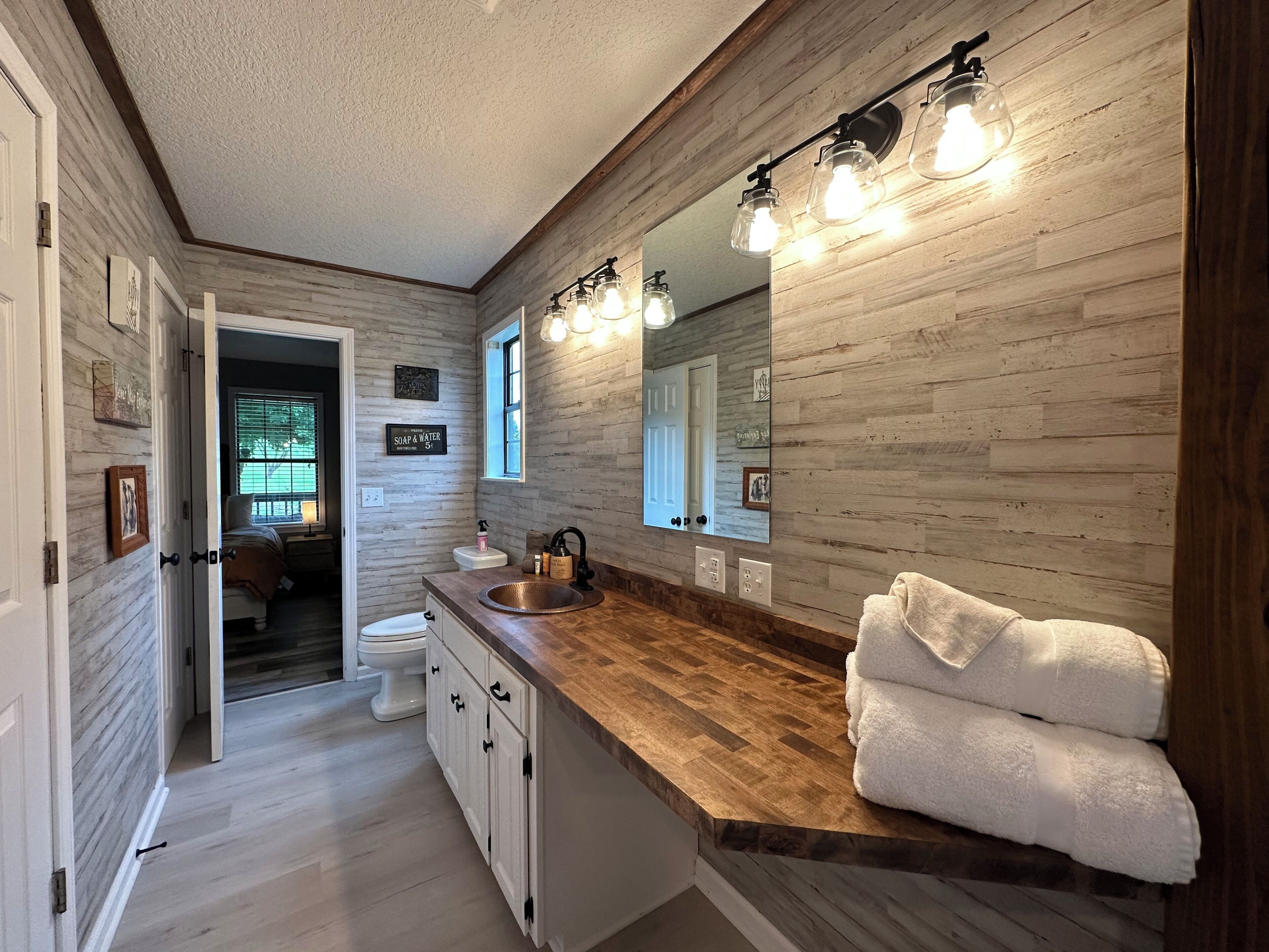 A bathroom with a wooden vanity, a large mirror, and a sink.