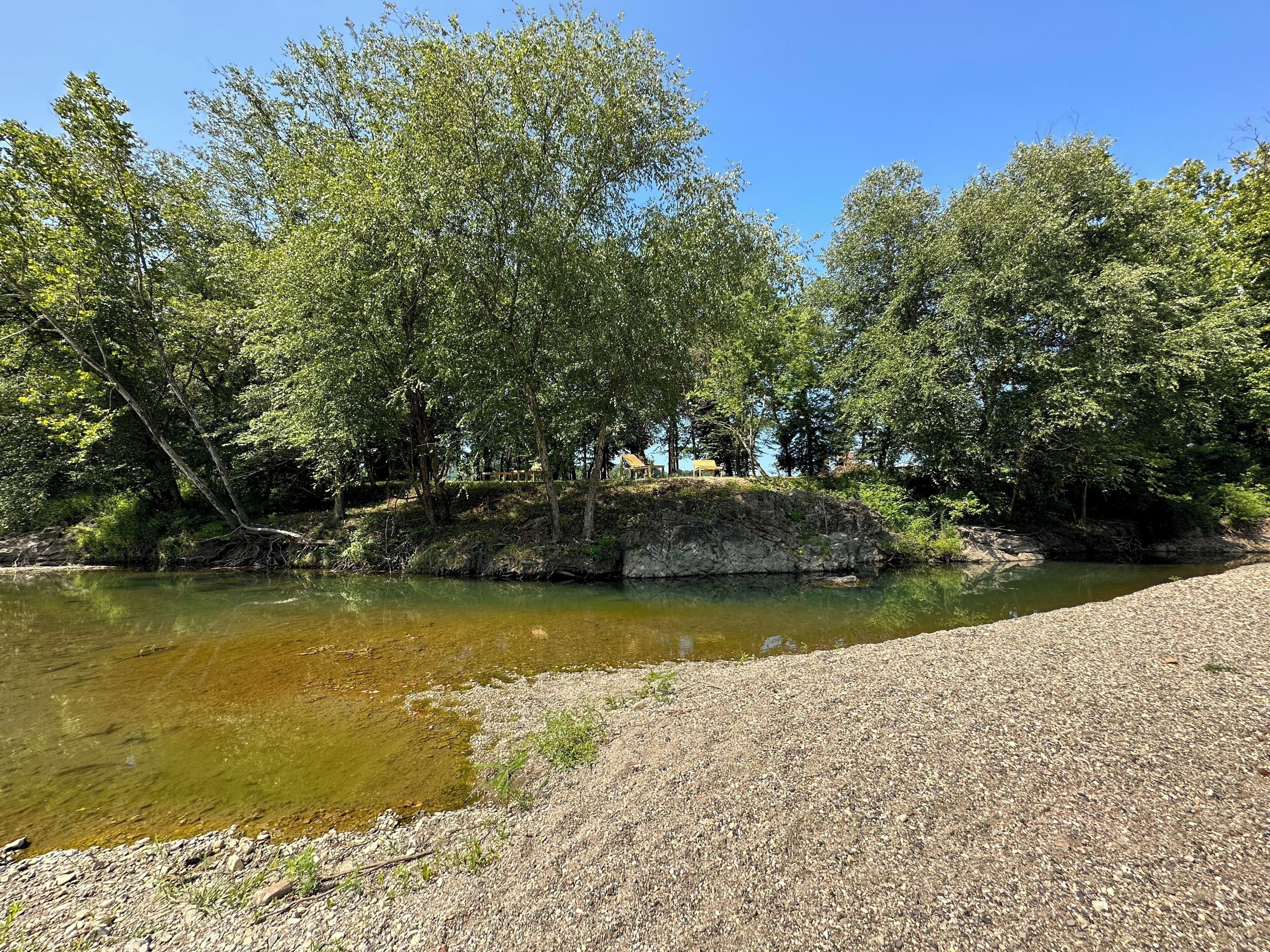 Un río con orilla rocosa y árboles.