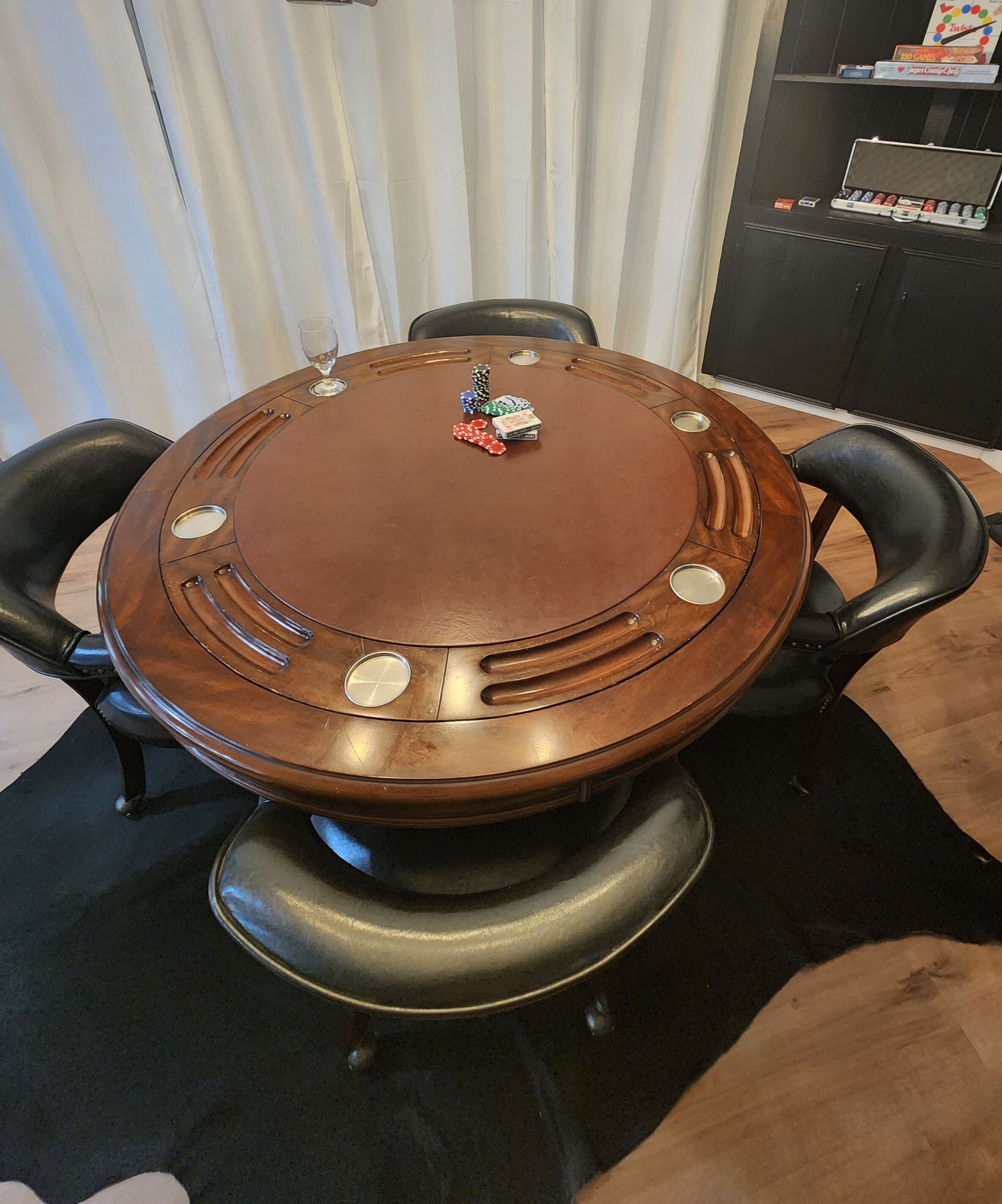 Een ronde houten tafel met pokerfiches en een kaartspel.